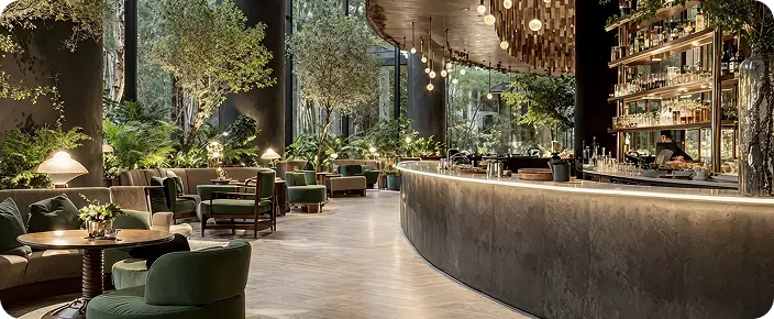 Contemporary bar and lounge interior with indoor greenery and illuminated counter.