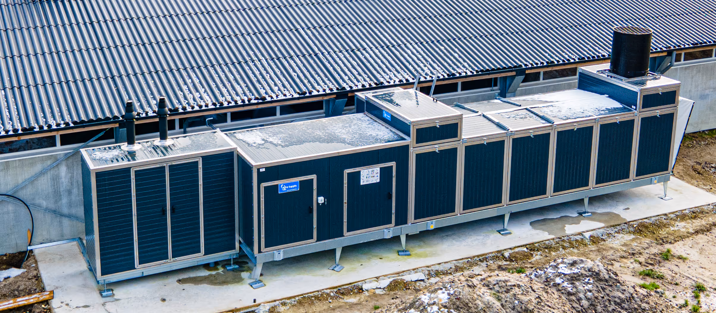 Grote industriële HVAC-installatie die buiten een gebouw is geplaatst, met sneeuw erop.