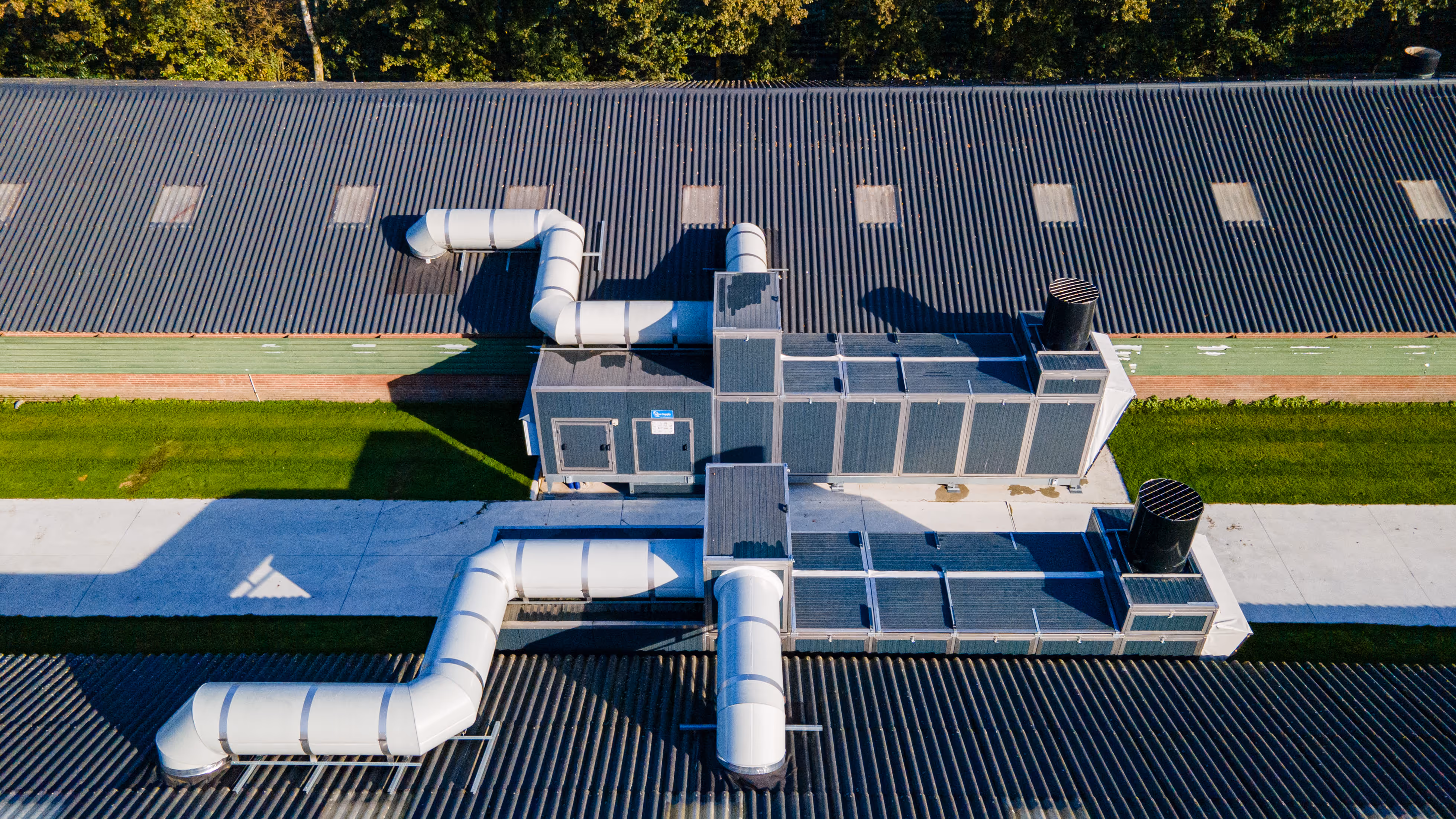 Luchtfoto van een industrieel HVAC-systeem met grote luchtkanalen op de daken van gebouwen met golfplaten.