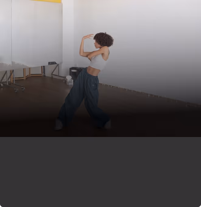 Woman in white crop top and baggy pants dancing in a studio with mirrors.