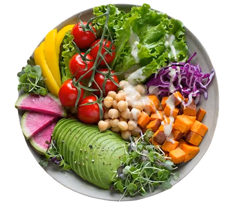 Bowl with avocado, cherry tomatoes, lettuce, mango, chickpeas, purple cabbage, sweet potato, and microgreens with dressing.