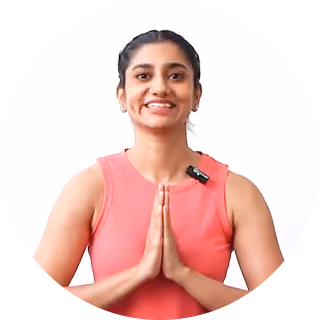 Smiling woman in pink sleeveless top with hands pressed together in a greeting gesture.