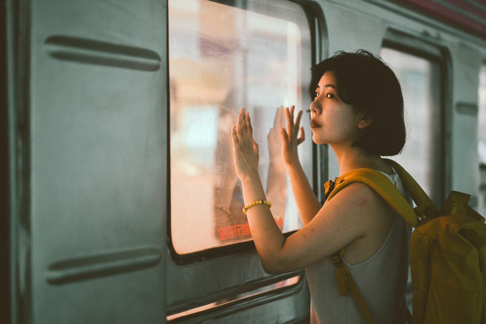 Une jeune femme avec un sac à dos regarde par la fenêtre d'un train