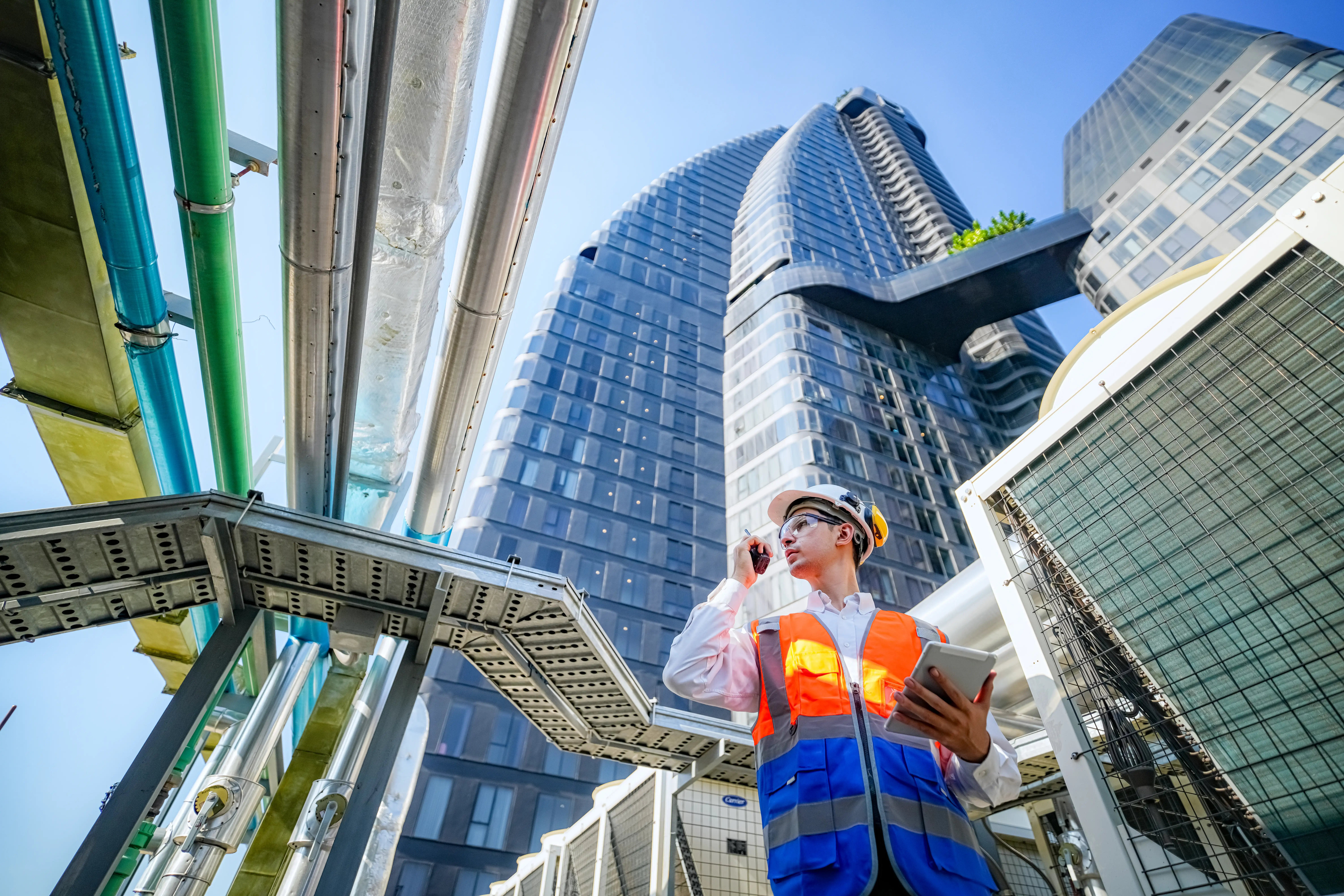 man on office building construction site using proptech on tablet, while talking on a walkie talkie