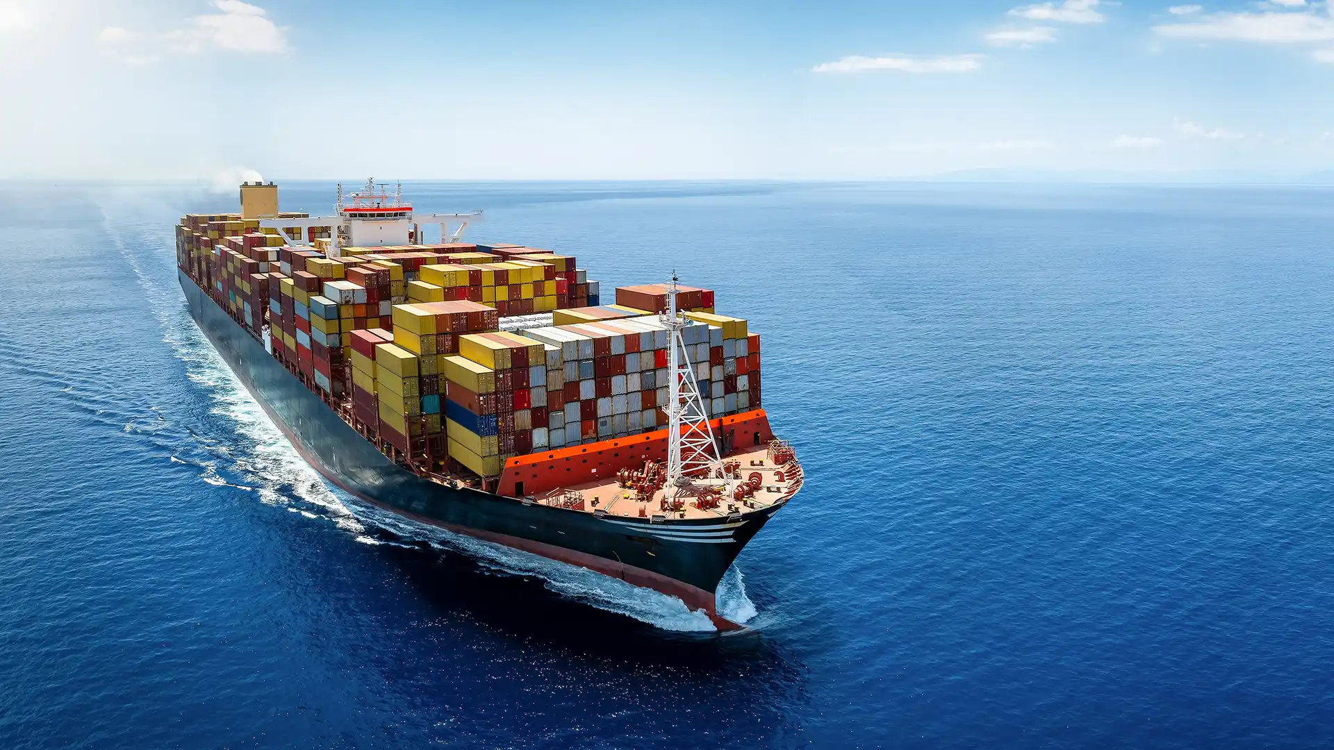 Container ship transporting goods across international waters under clear blue sky