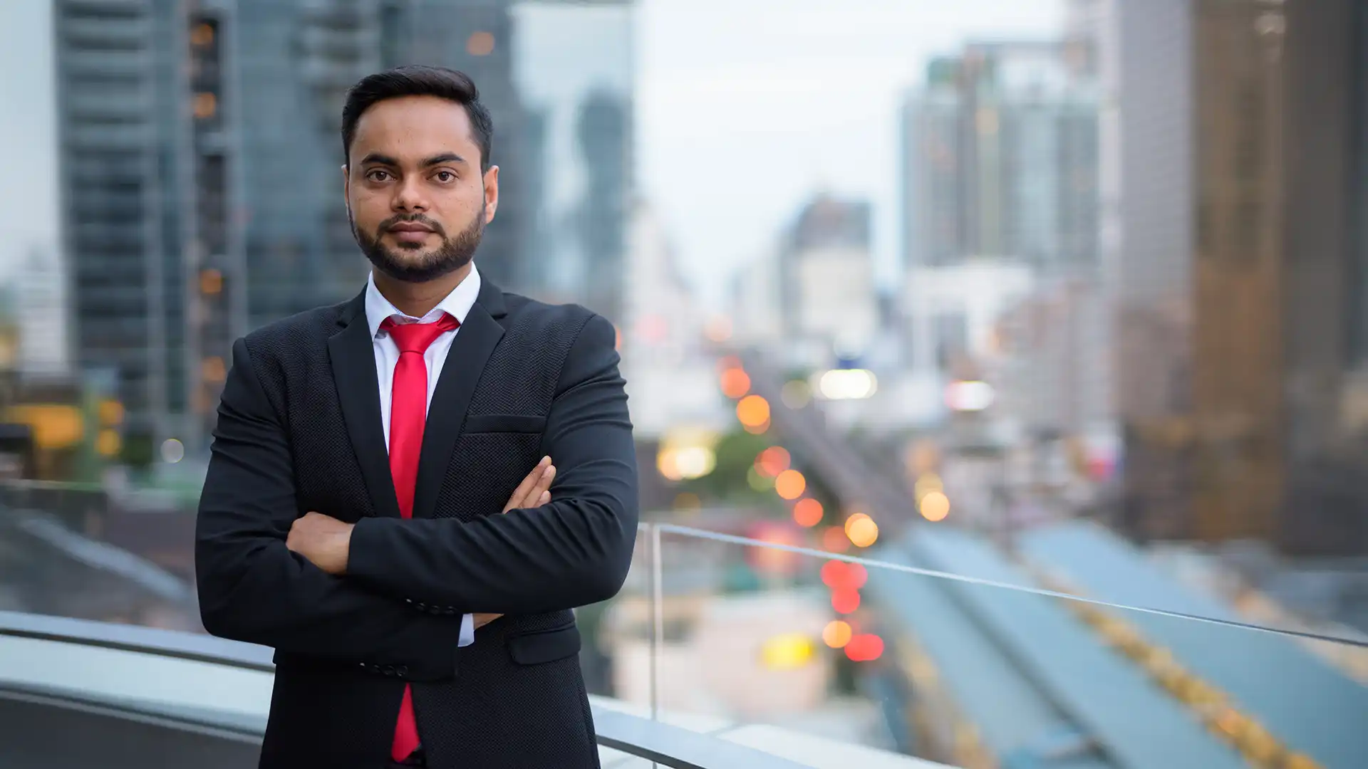 Indian entrepreneur in formal attire standing on Dubai balcony with city skyline at night