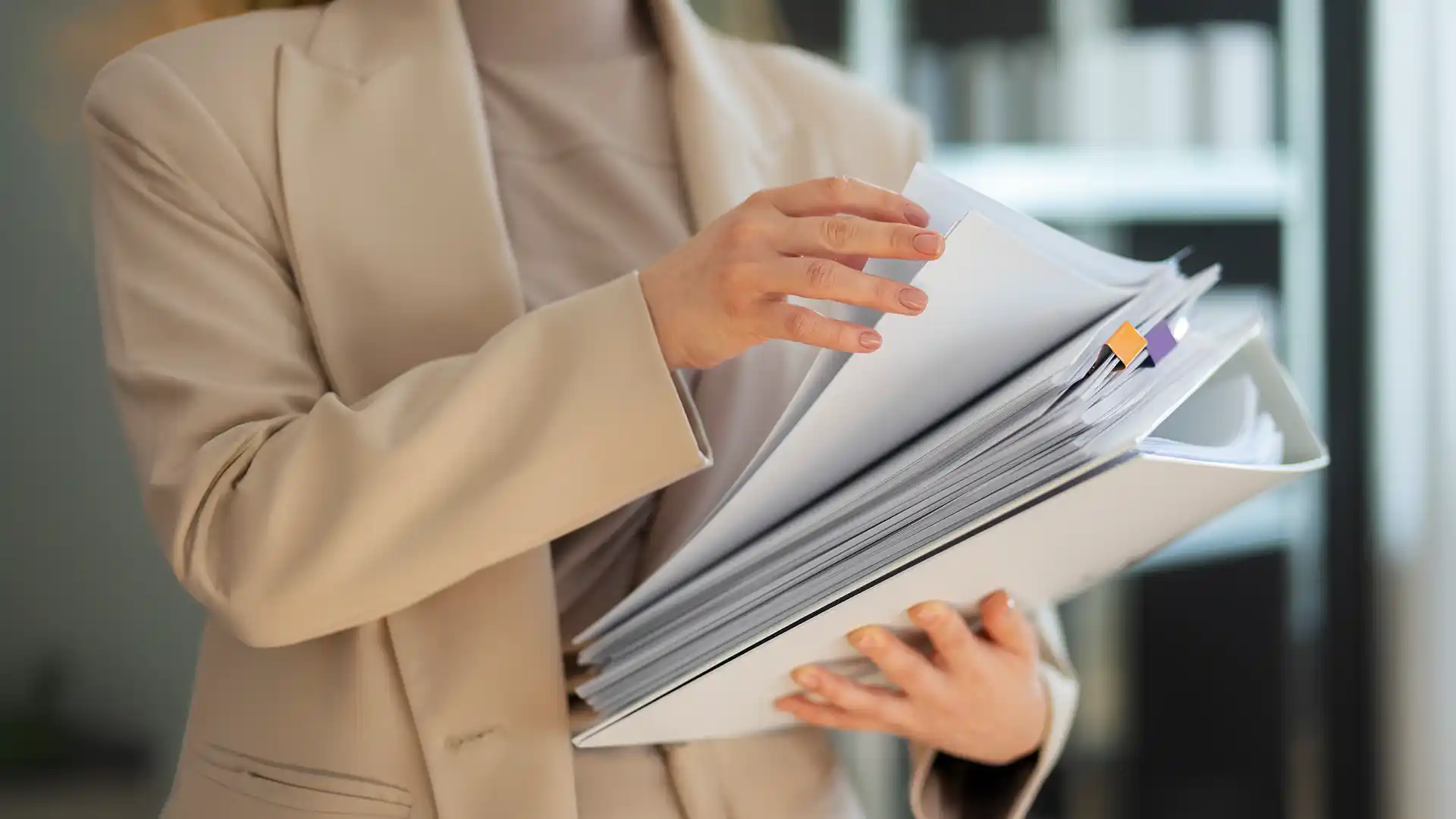 Man in beige suit holding a pile of papers