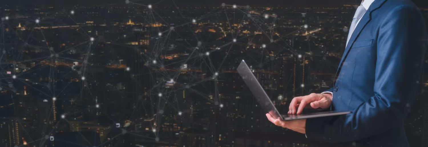  A professional using a laptop, with an illuminated city skyline and digital network graphics, representing advanced business technologies and innovative solutions.