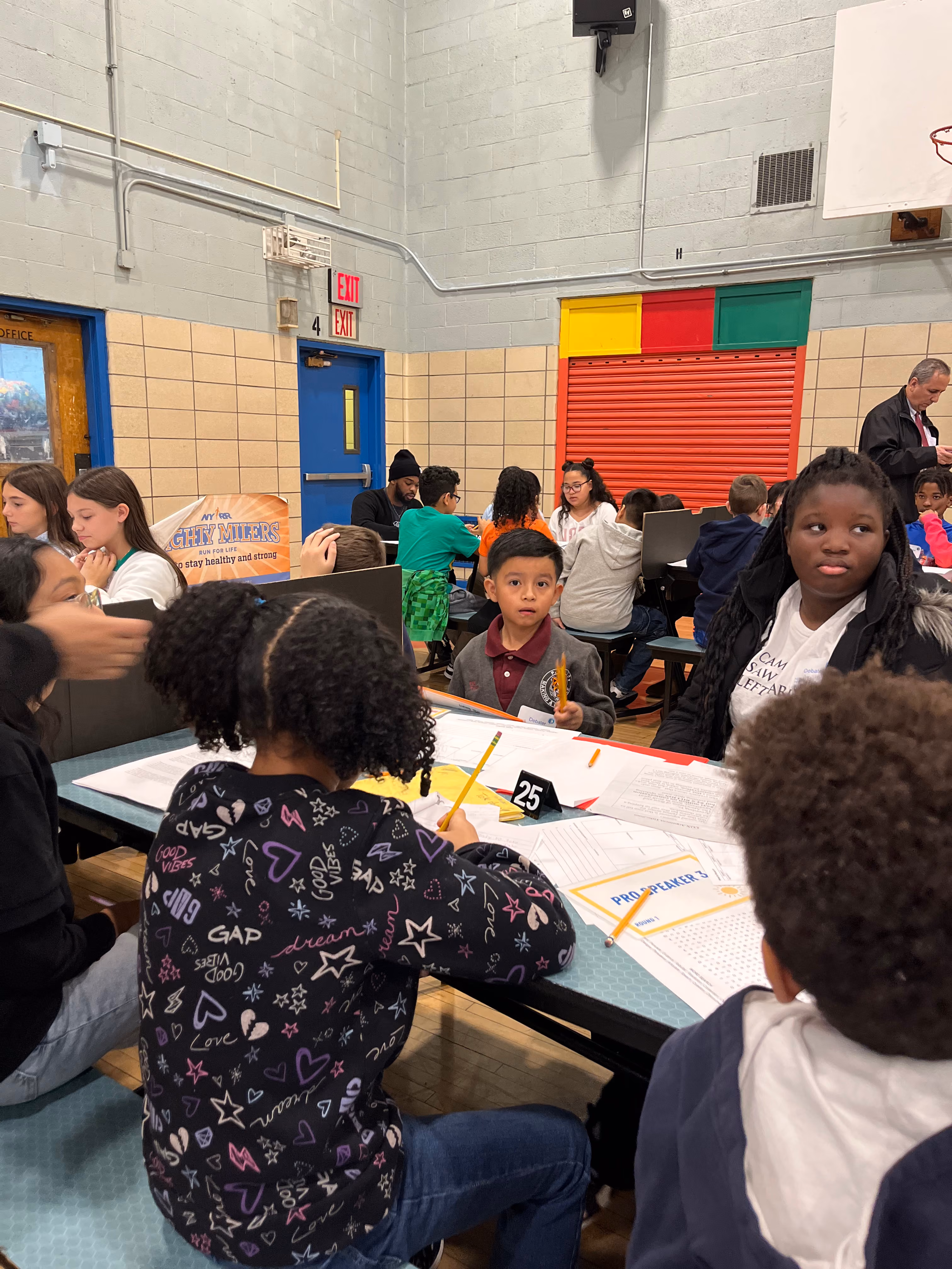 Students working at tables during a school gymnasium competition event