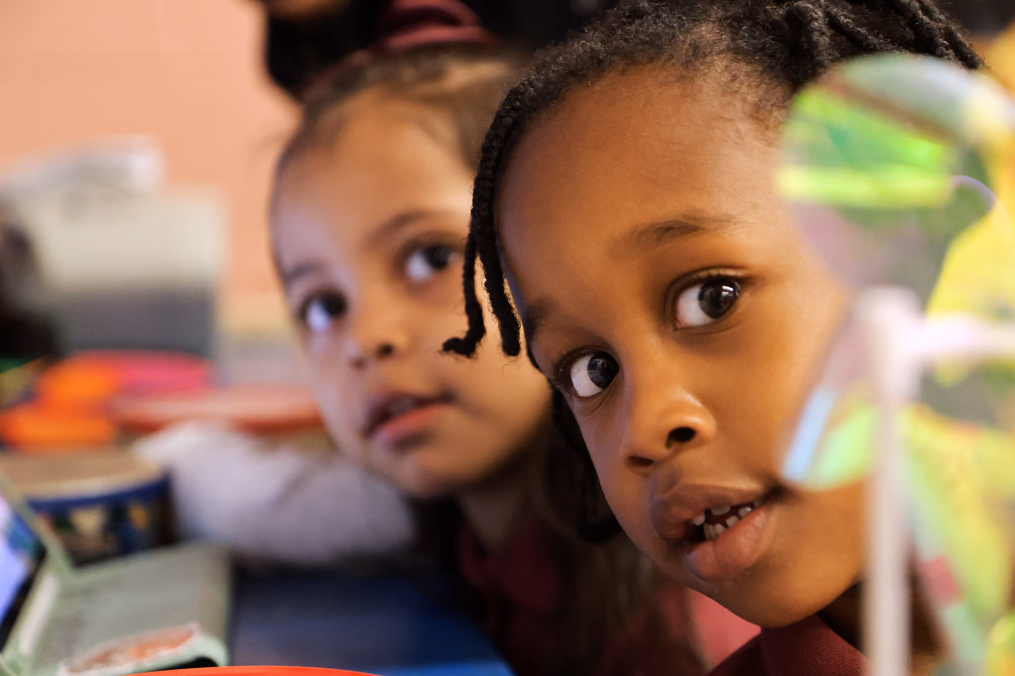 Two young students looking curiously at a classroom activity