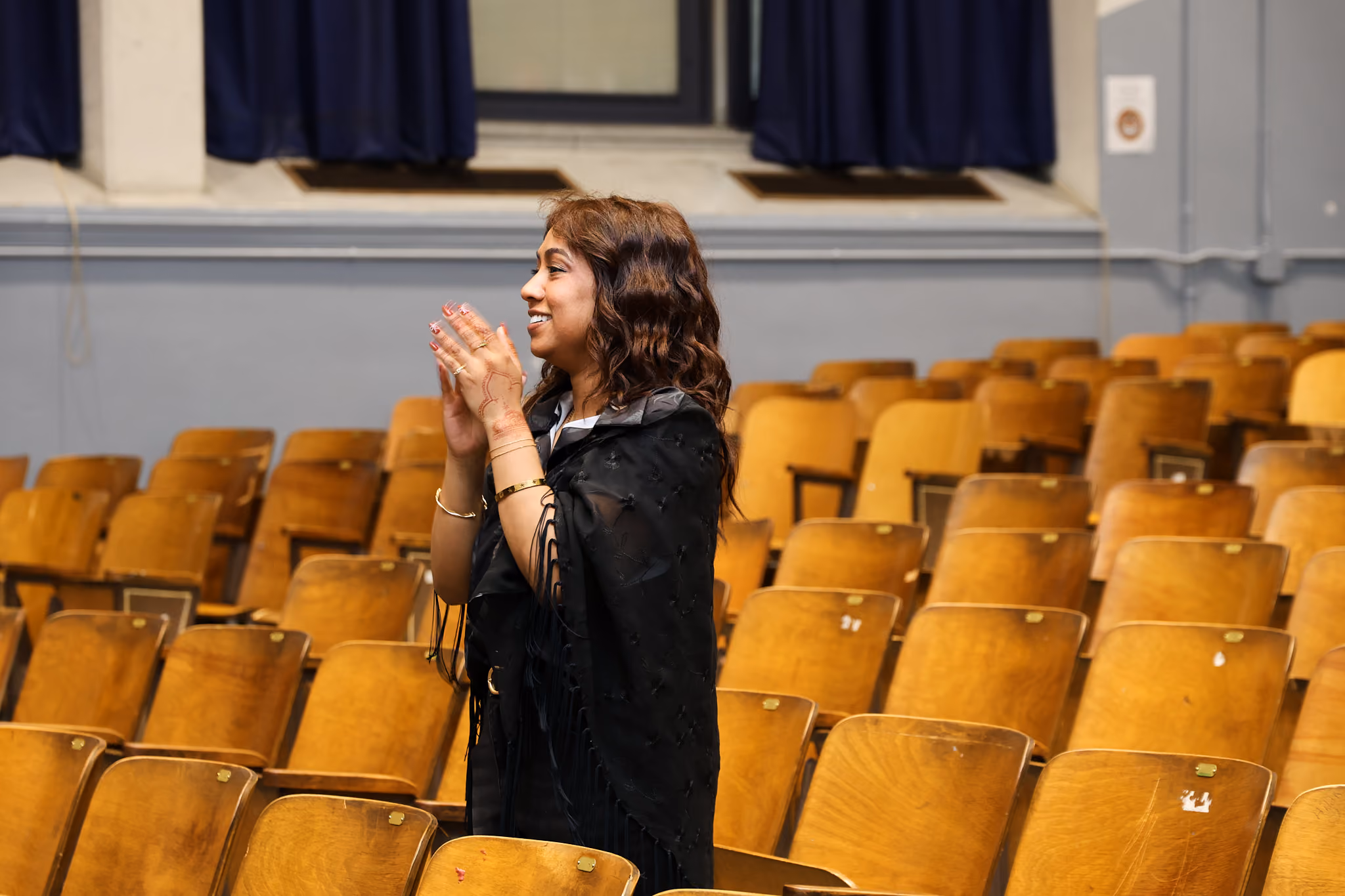Student clapping and smiling while standing in school auditorium