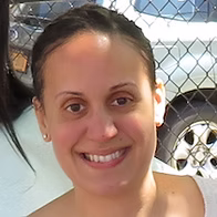 Ms. Rodriguez smiling outdoors near a chain-link fence