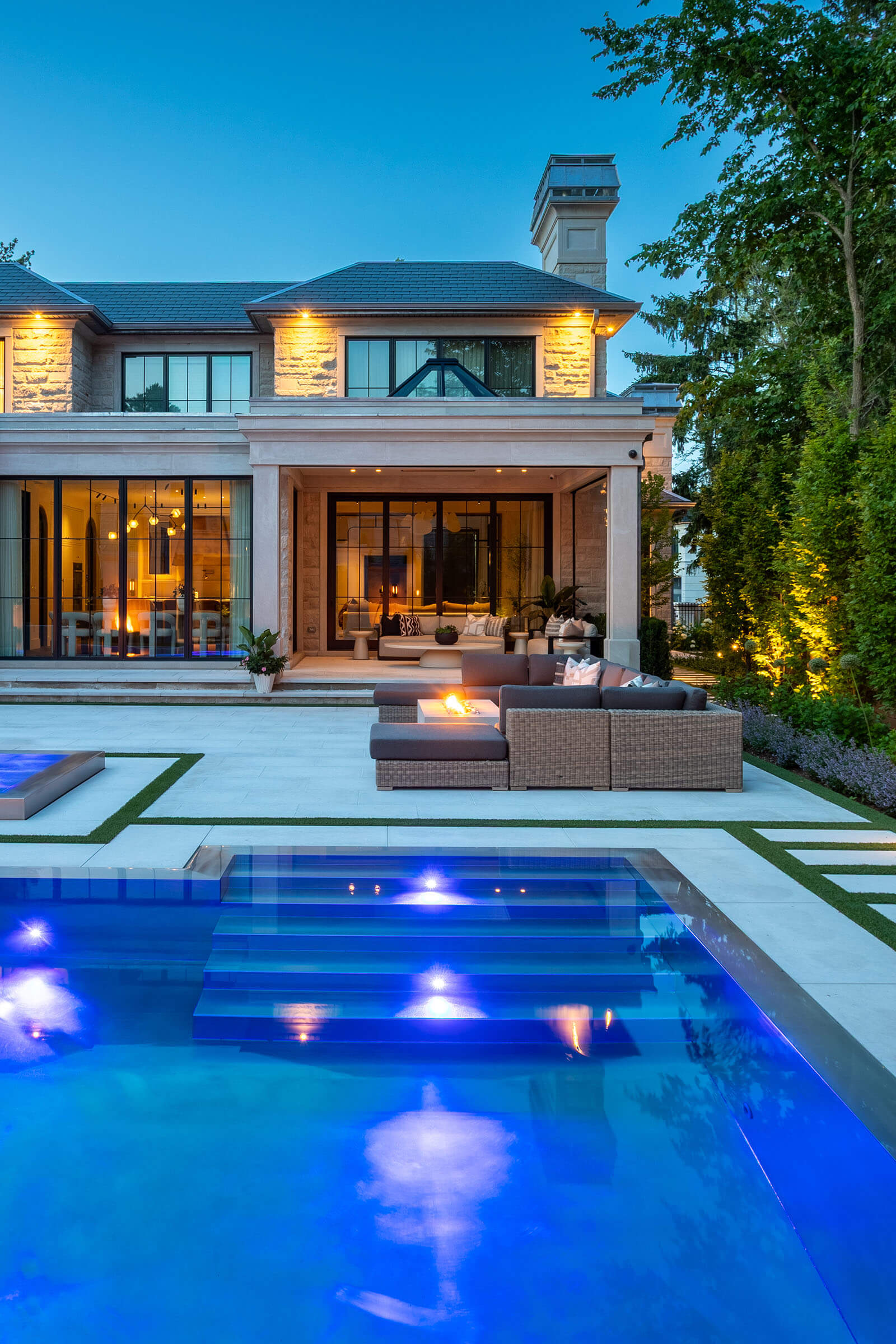 Modern backyard with swimming pool, two lounge chairs under a large white umbrella, and a gray sofa with cushions.
