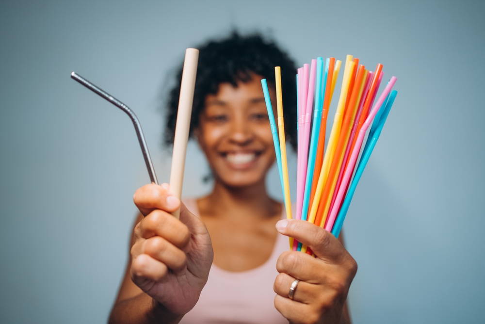 Smiling black woman with curly hair holding out many colored straws
