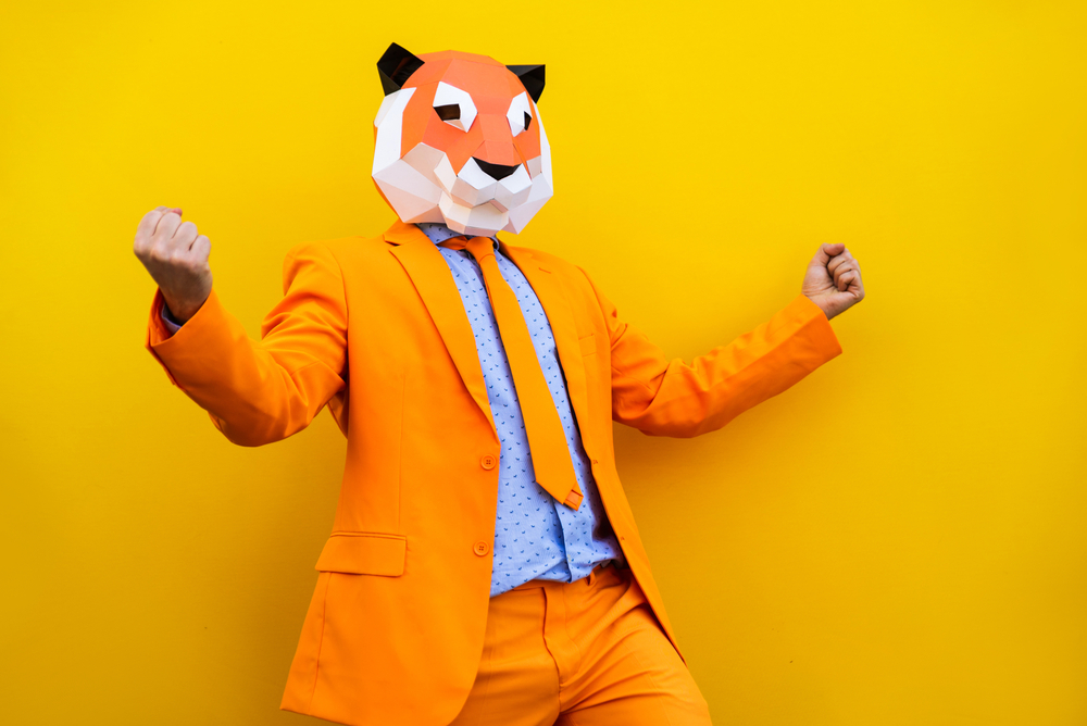 Man in a bright orange suit wearing a tiger origami mask