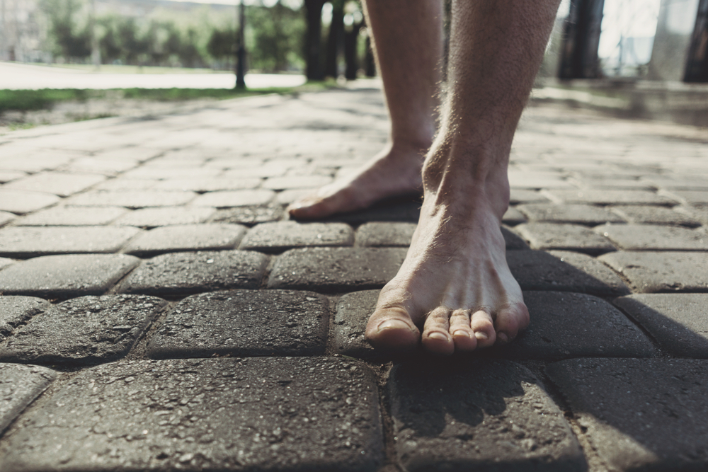 Bare men's feet ankle down stepping on to pavement