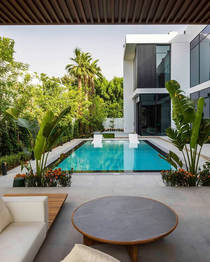 Luxury outdoor setting in a resort with a rectangular pool, and a daybed with cushions