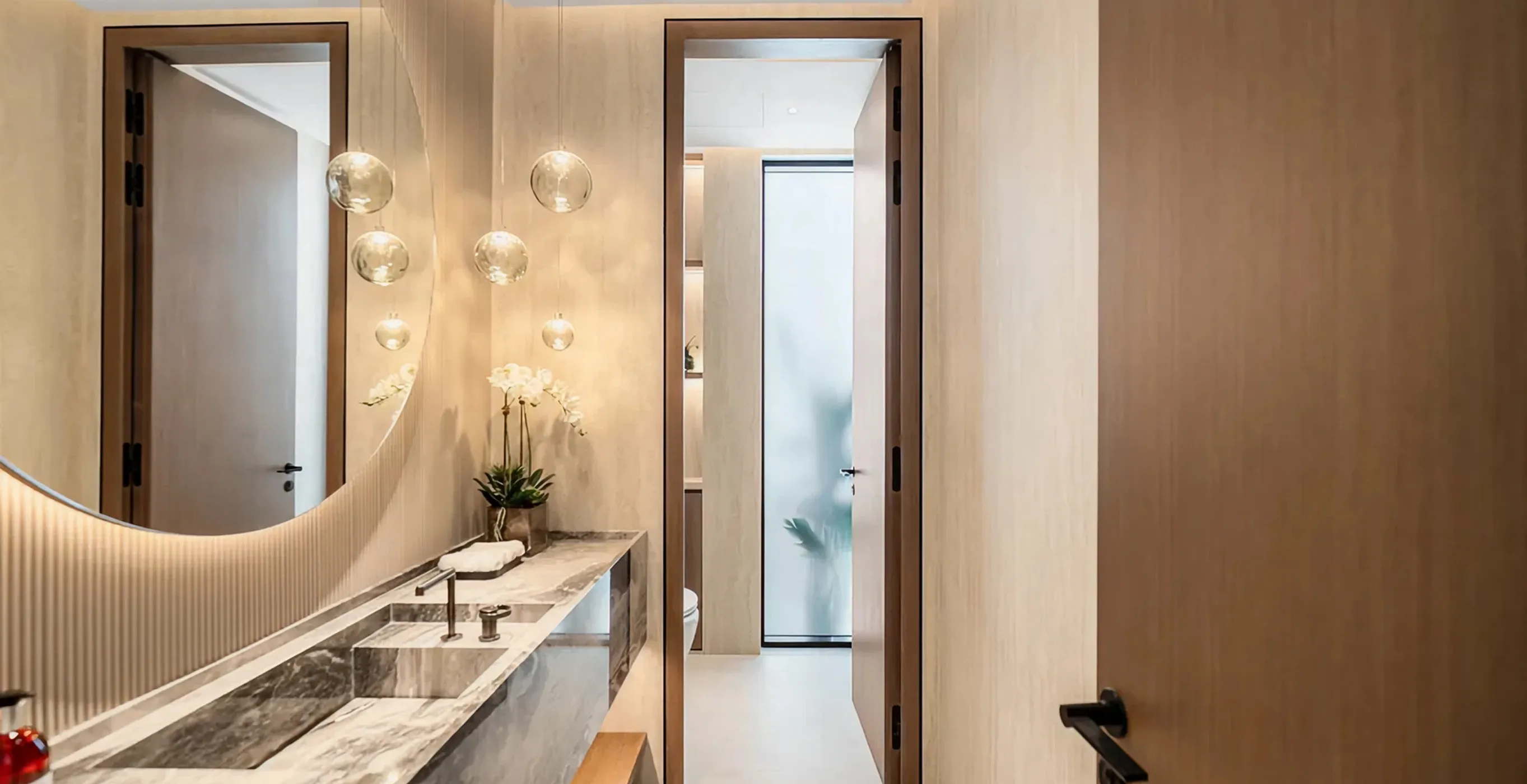Modern villa bathroom interior in Palm Jumeirah with marble double vanity and glass accents.