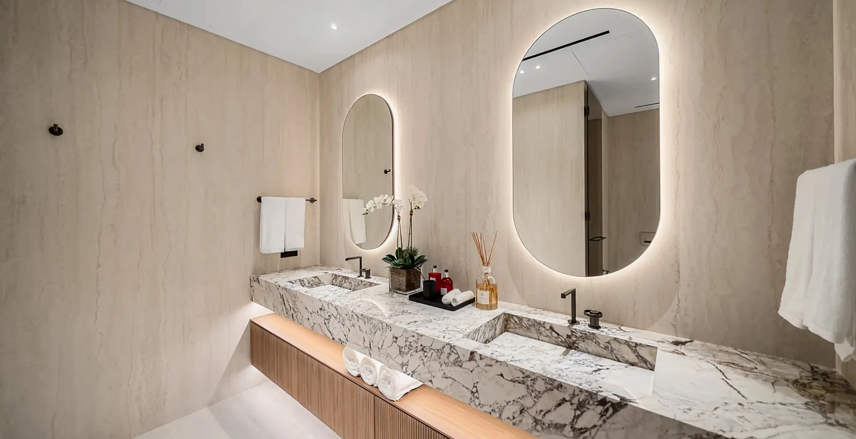 Luxury villa bathroom interior with marble double vanity and backlit mirrors in Palm Jumeirah.