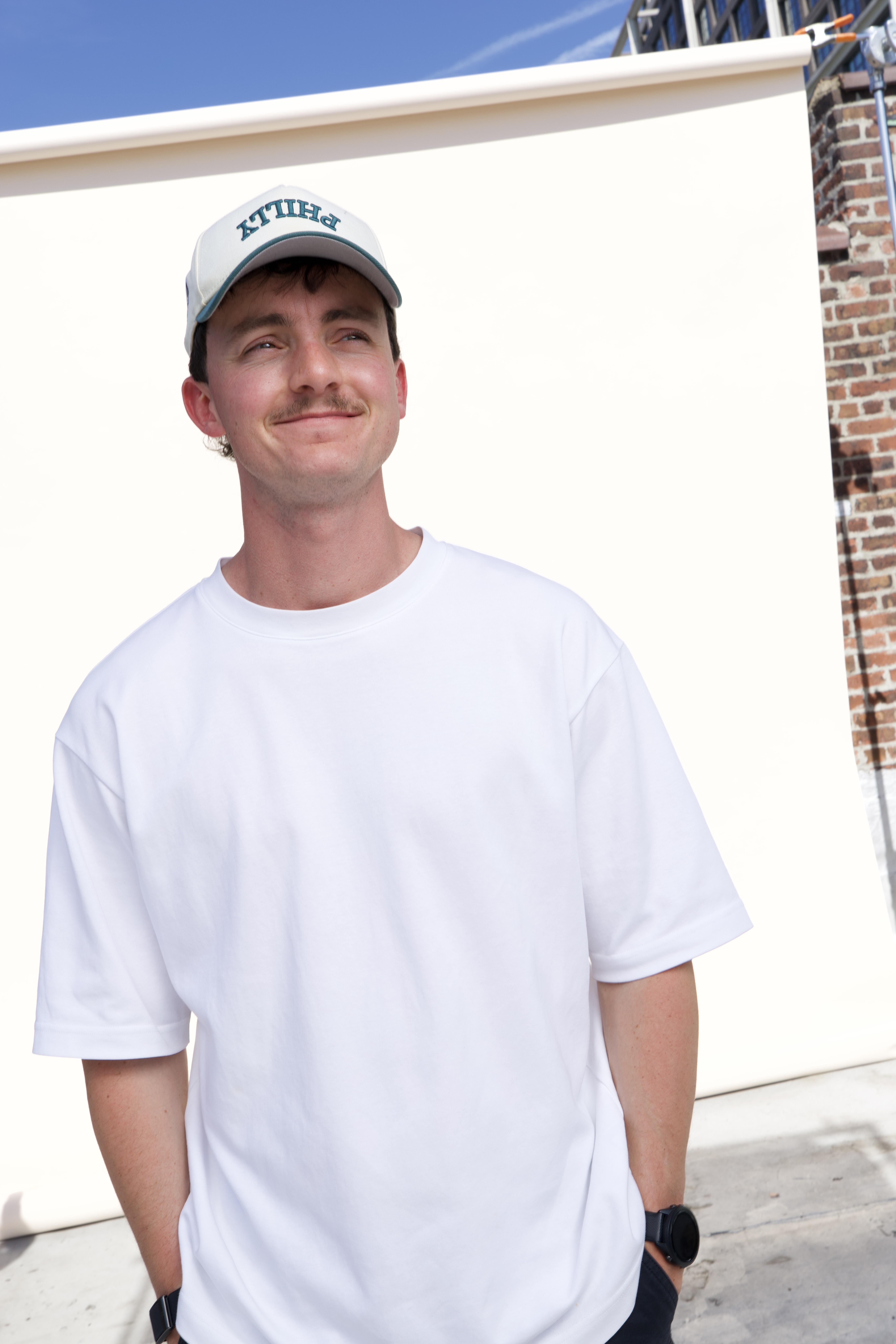 Arnaud, founder of MNTRA, smiling in a white Philly cap and white t-shirt
