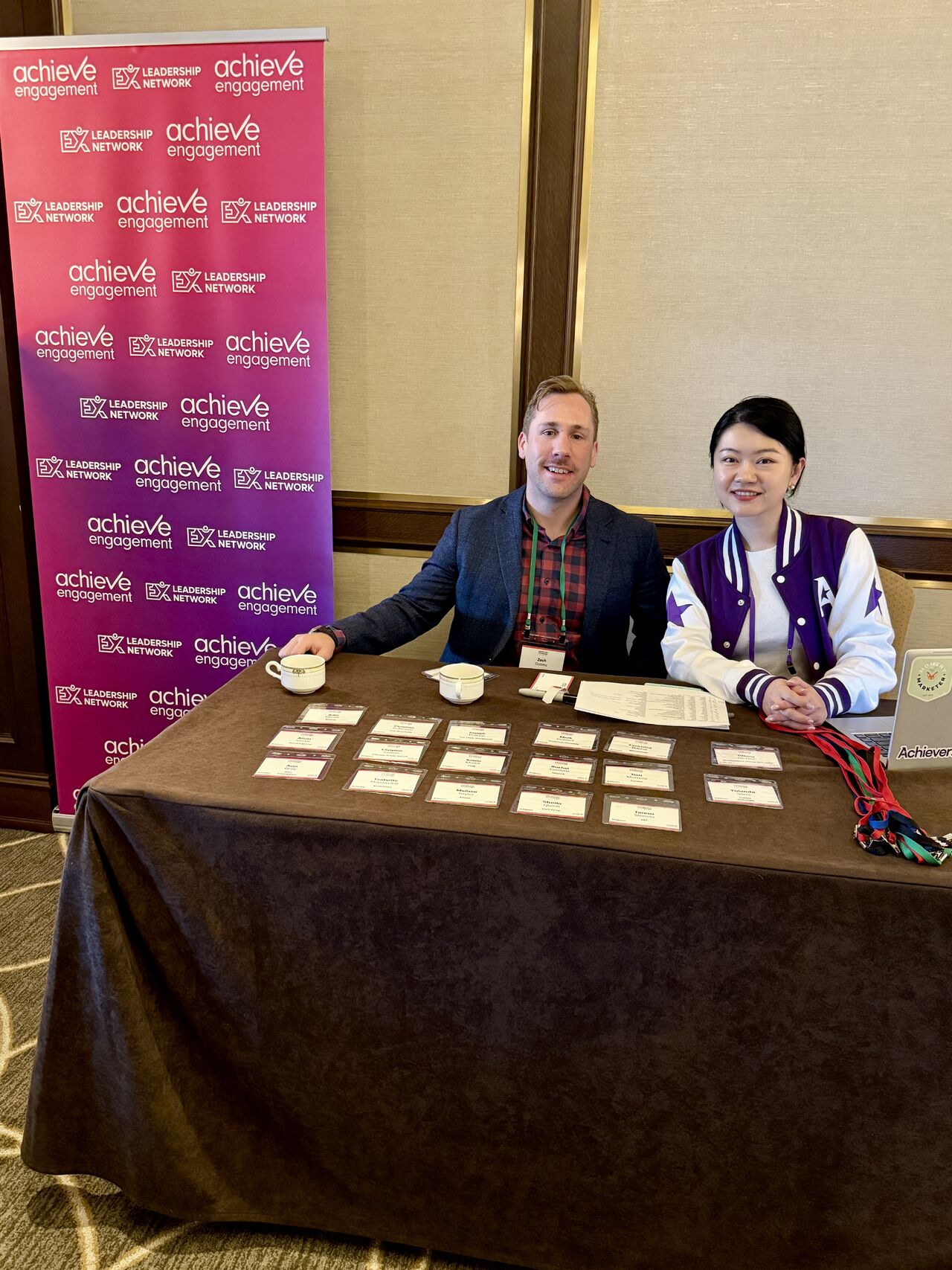 Two people at Achieve Engagement Leadership Network conference registration table