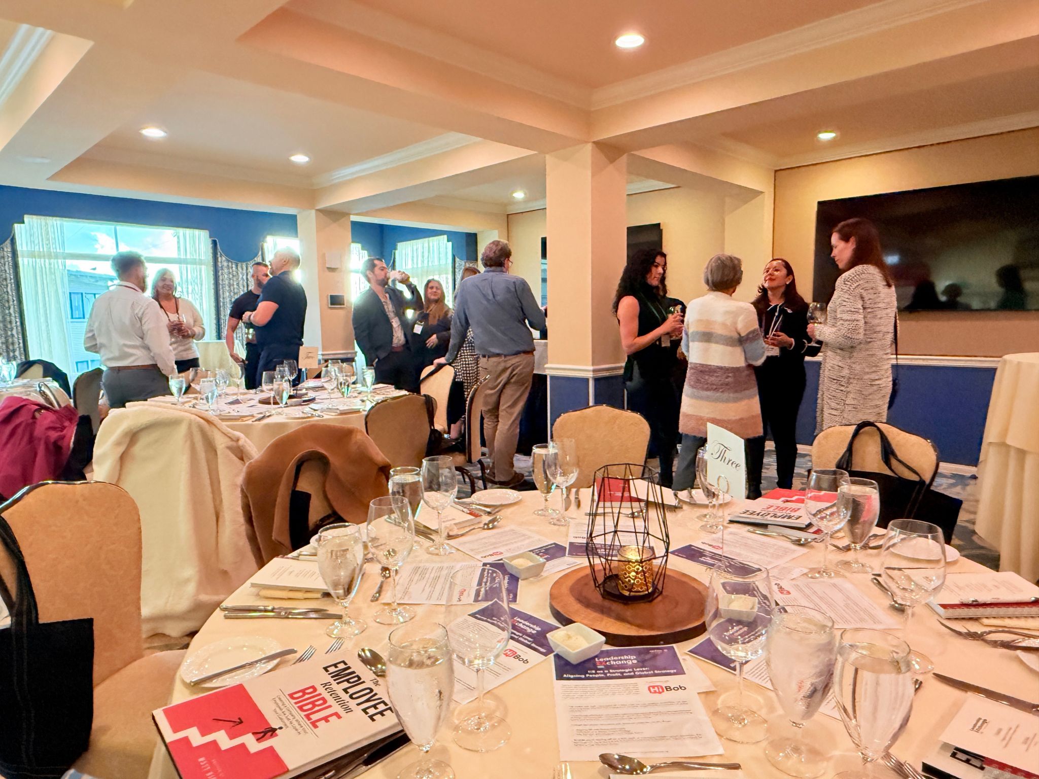 Professional networking event with tables, drinks, and people mingling
