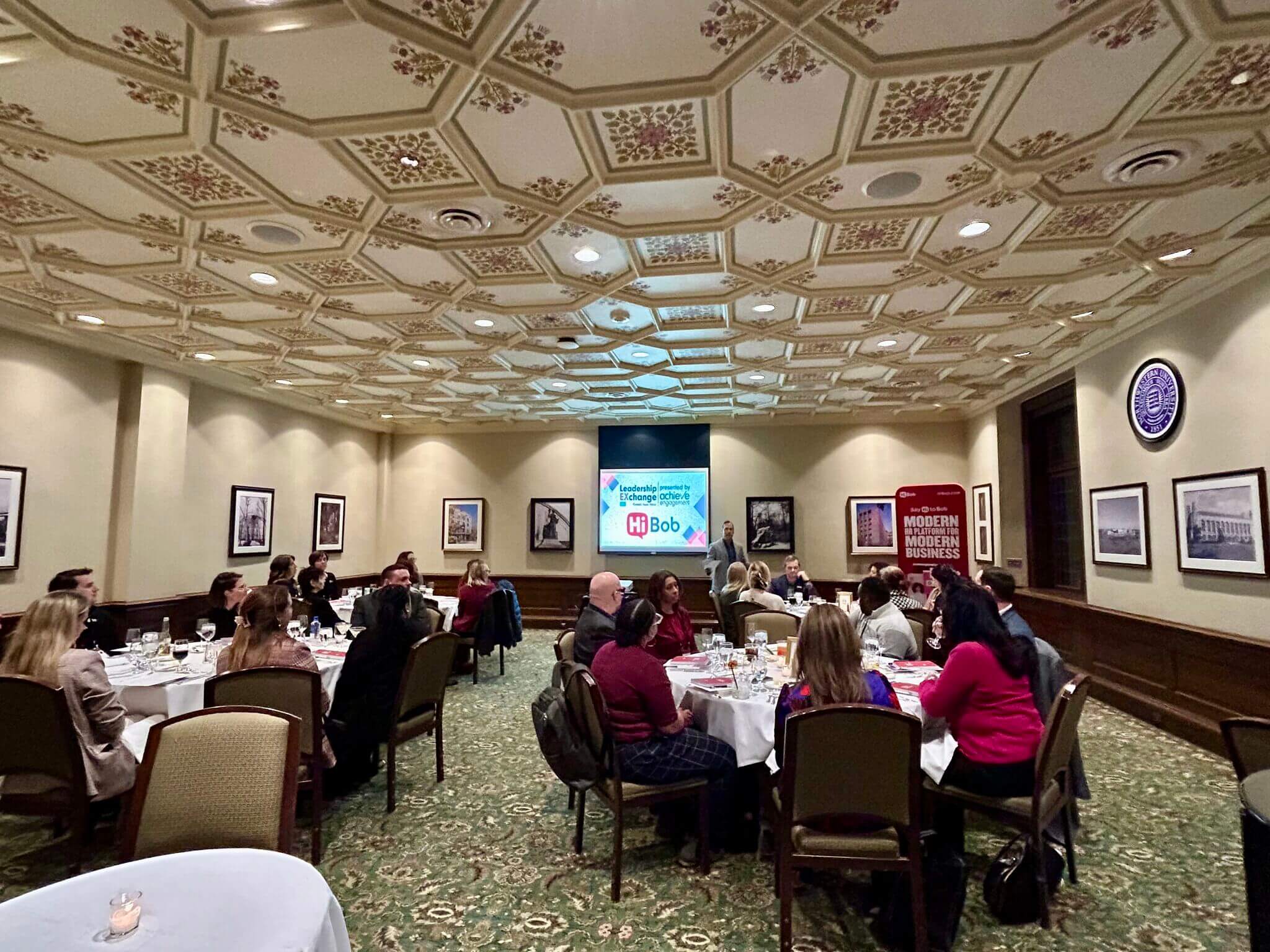 Business conference in elegant room with ornate ceiling and HR Bob presentation
