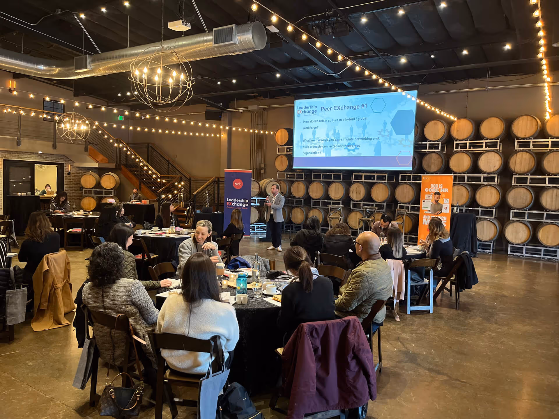 Leadership conference in a winery with string lights and presentation screen