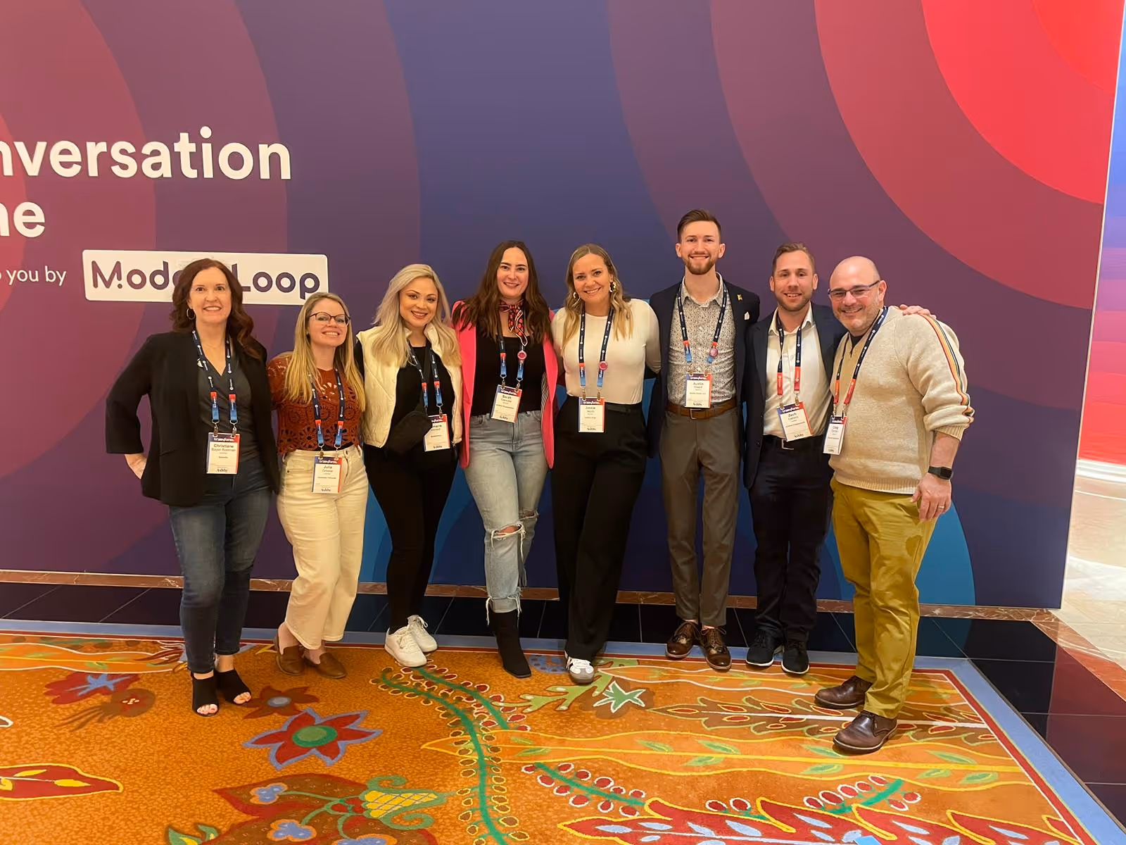 Group of professionals posing at conference with colorful ModLoop backdrop