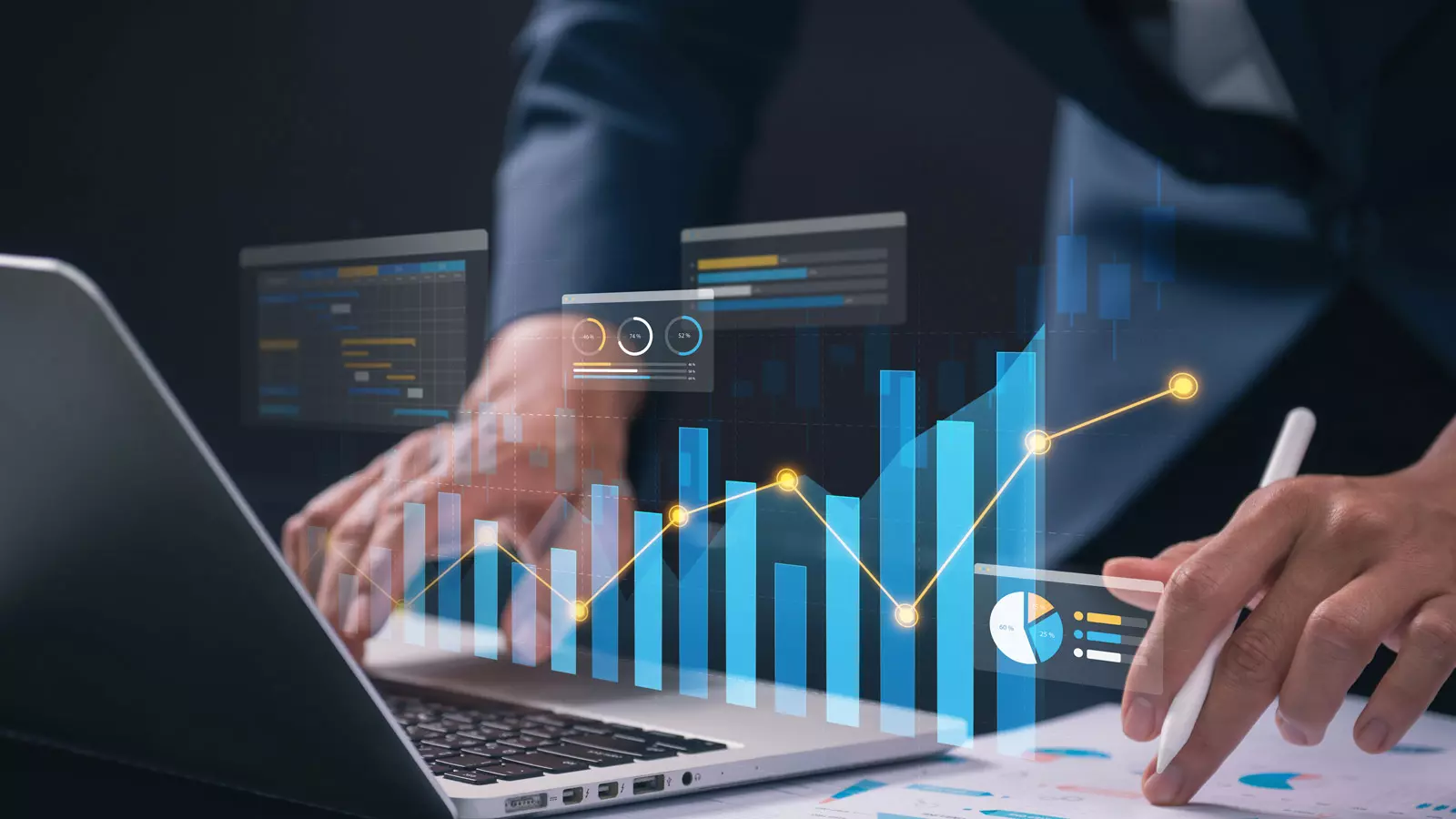 Holographic charts and data metrics floating over a laptop and tablet screen. A professional analyzing real-time demand forecasting models using digital tools.