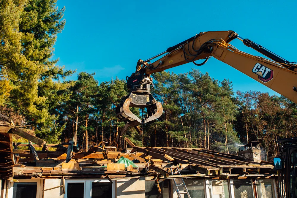 Bagger mit Greifarm beim Abriss eines Bungalows in Berlin