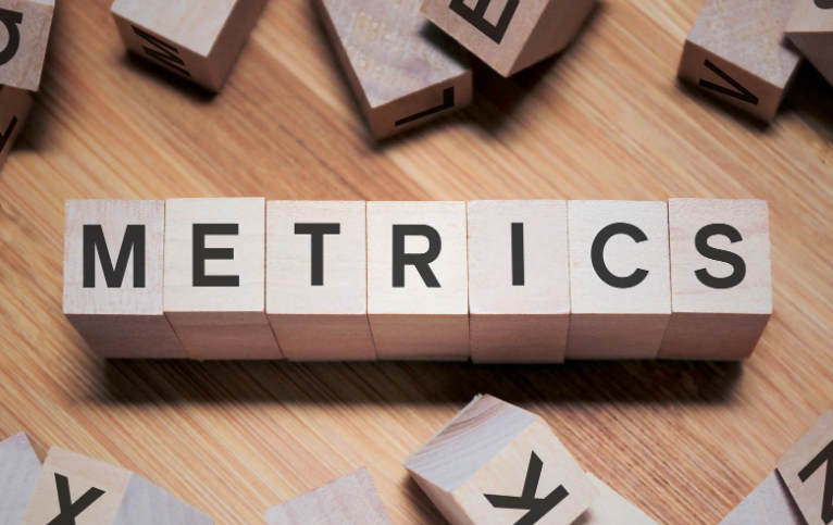 Wooden letter blocks spelling “METRICS” on a desk, symbolizing standardized metrics and KPIs in marketing analytics. i-radius