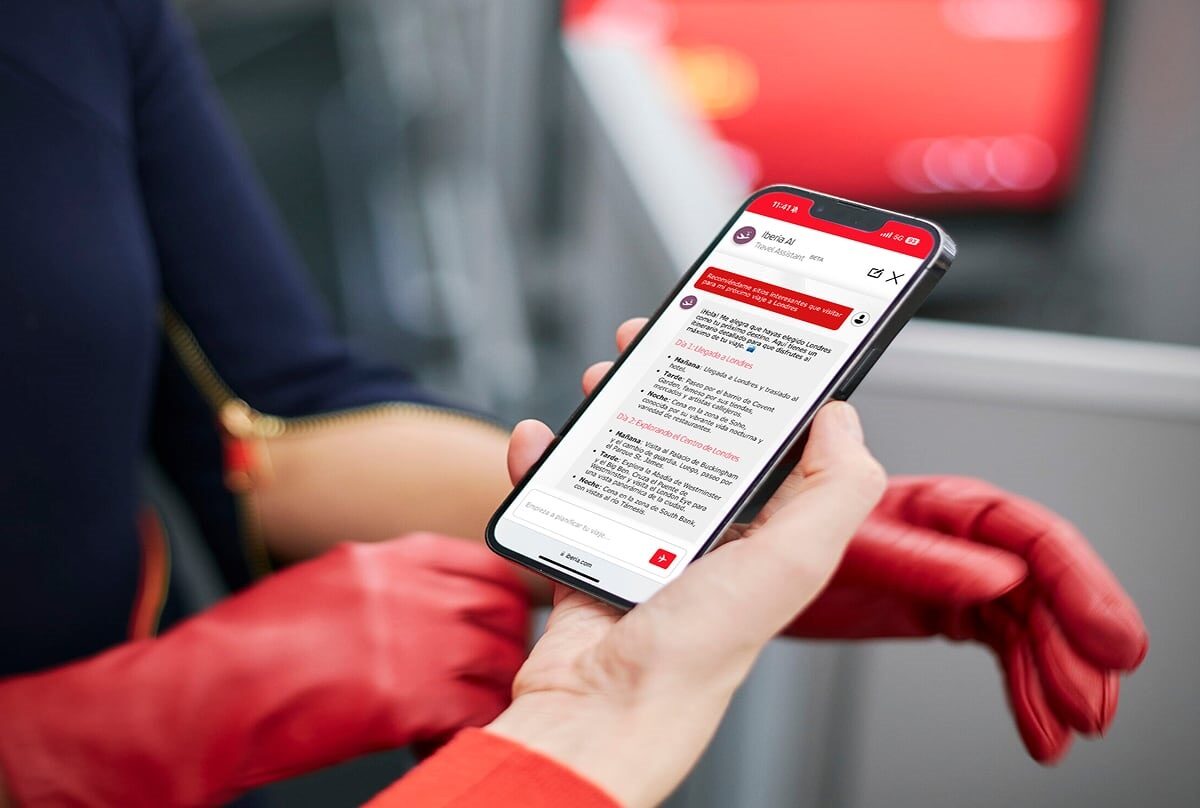 Una mano con guantes rojos sostiene un teléfono móvil que muestra recomendaciones de viaje de Iberia AI para visitar Londres, con texto en español que detalla un itinerario de viajes dividido en días y partes del día.