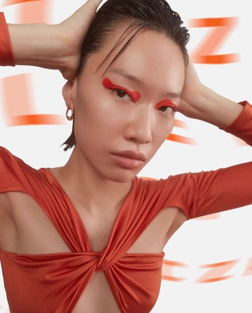 woman posing with hands on head wearing a knotted shirt