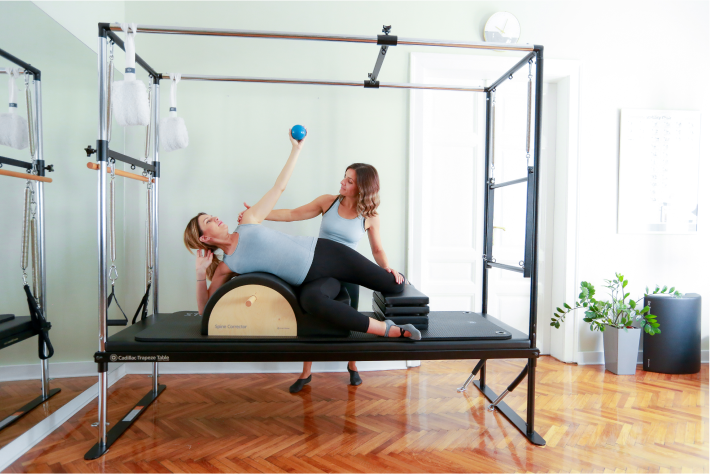 Pilates za trudince - slika pokazuje trudnicu koja trenira na reformer spravi za pilates