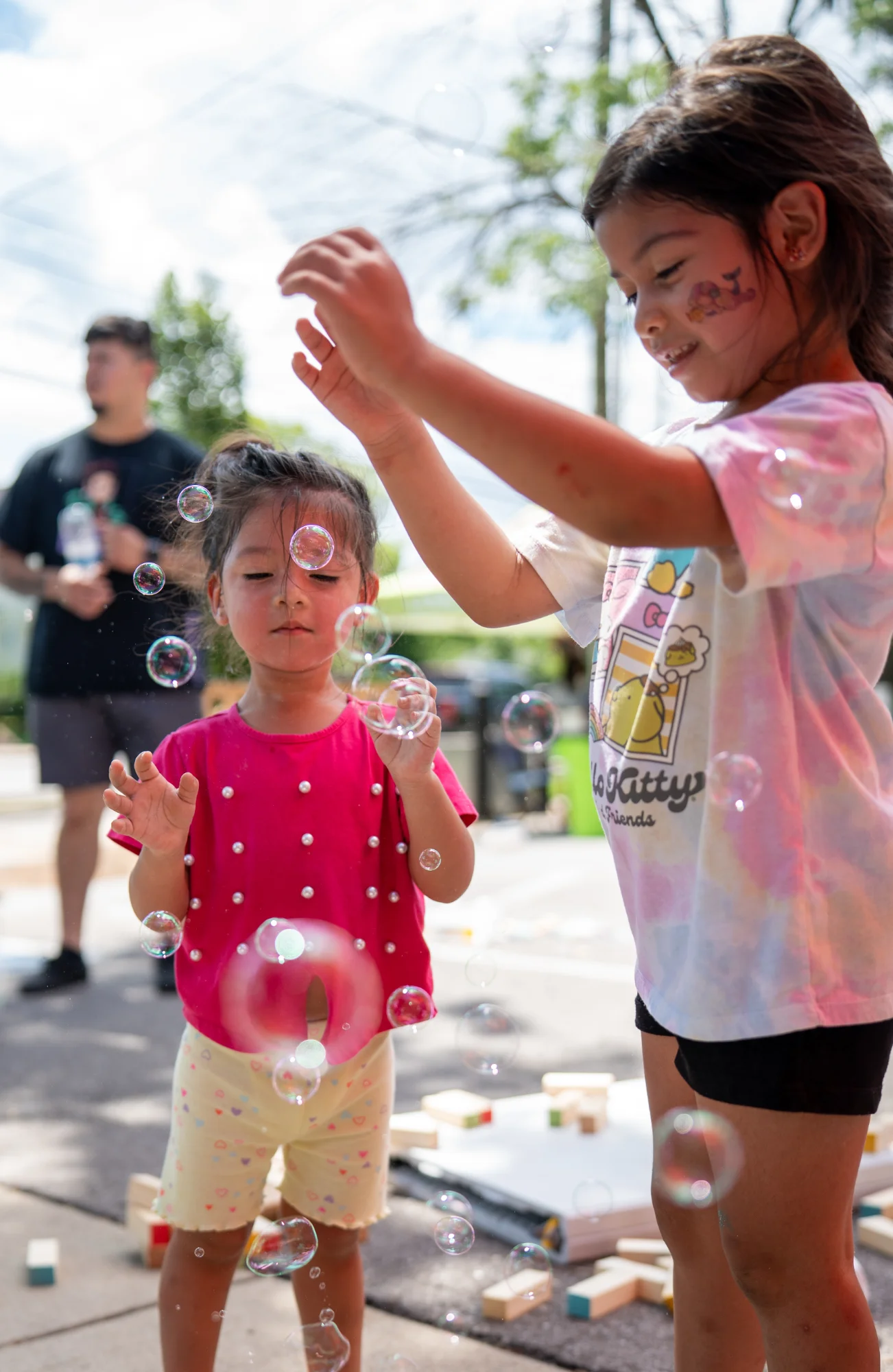 Two children play with bubbles in front of another community member at The School Store