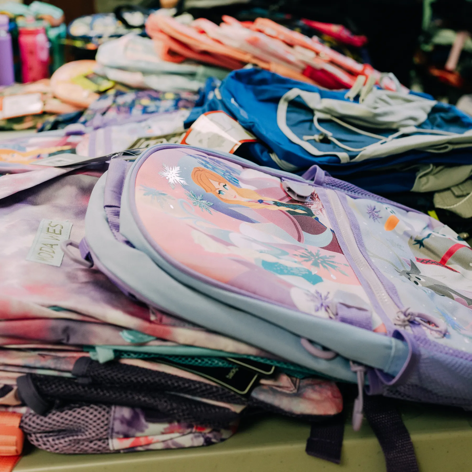 A table shows rows of donated backpacks for The School Store event