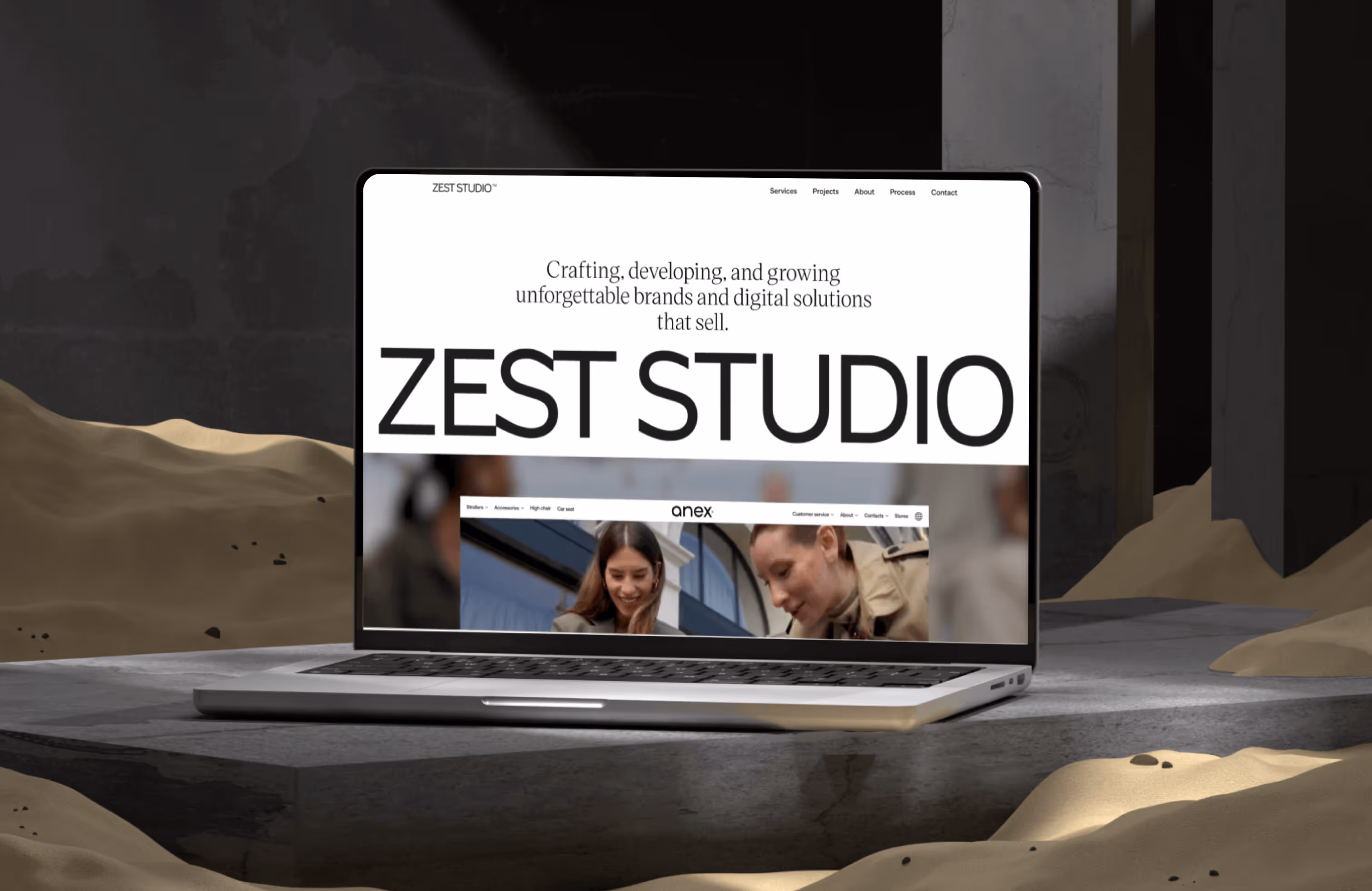 MacBook displaying Zest Studio graphic design website on modern desk with abstract sculptures.