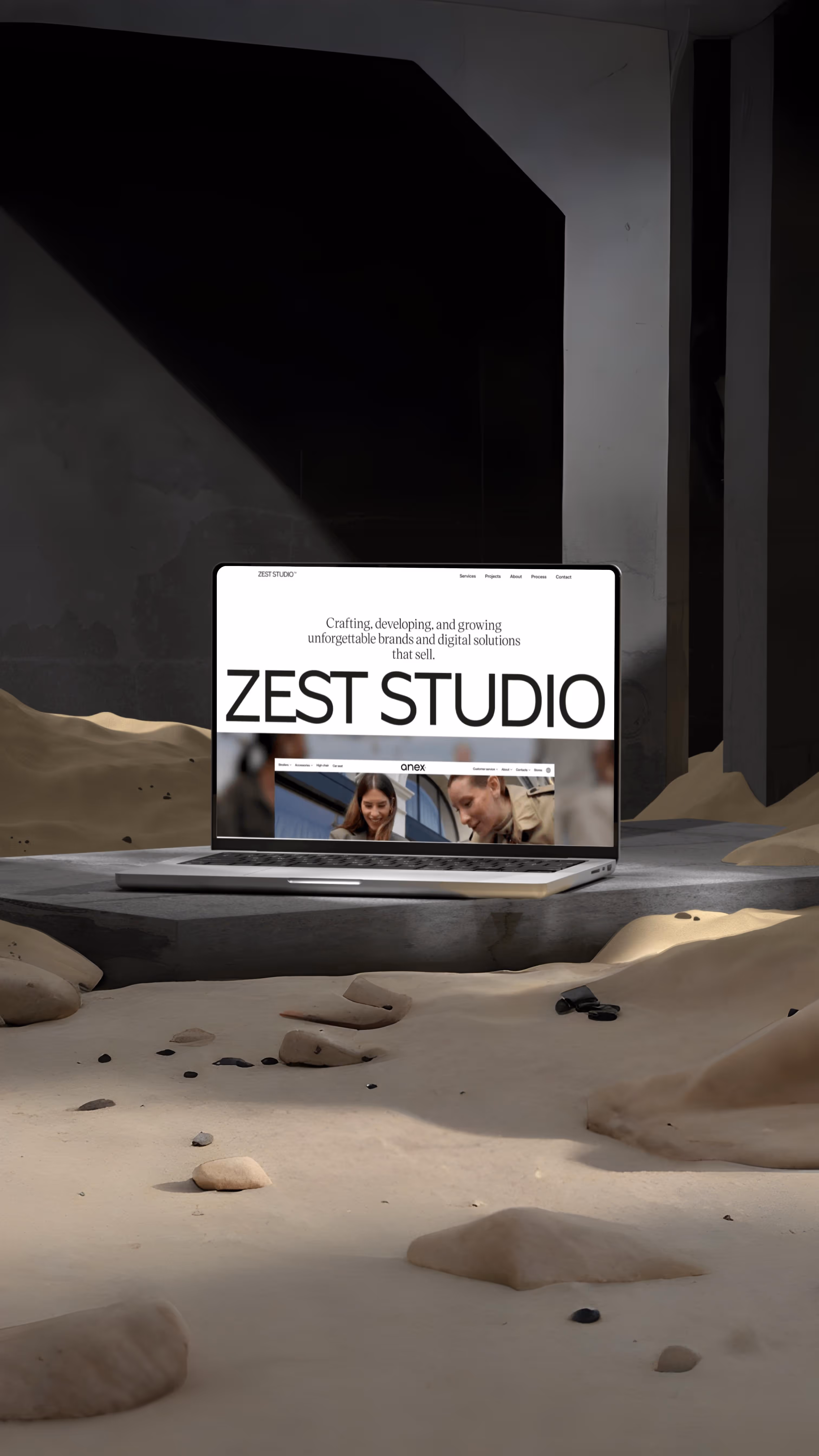 MacBook displaying Zest Studio graphic design website on modern desk with abstract sculptures.