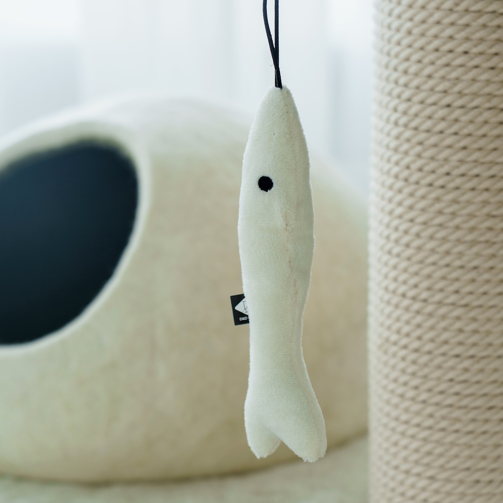 The cord of a hanging toy fastened under a fur-topped Kikska platform