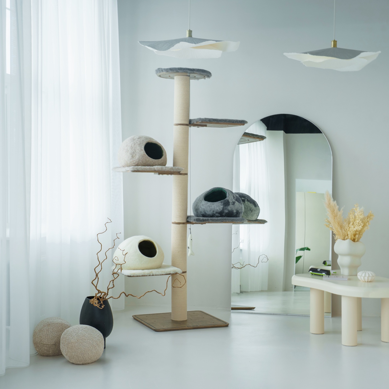 Tall Kikska cat tree with grey faux-fur platforms and three wool caves in a bright room