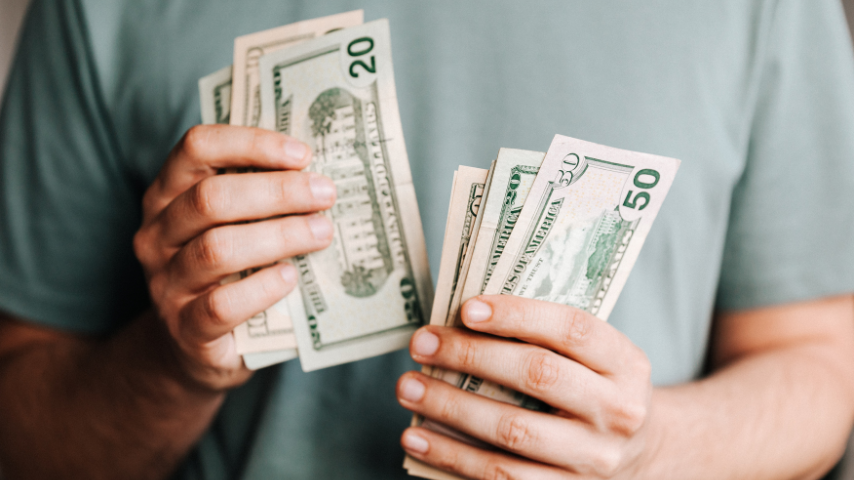 Persona sosteniendo billetes de dólares estadounidenses en ambas manos, simbolizando manejo de dinero. Ilustra el artículo: Cuentas en dólares en México.