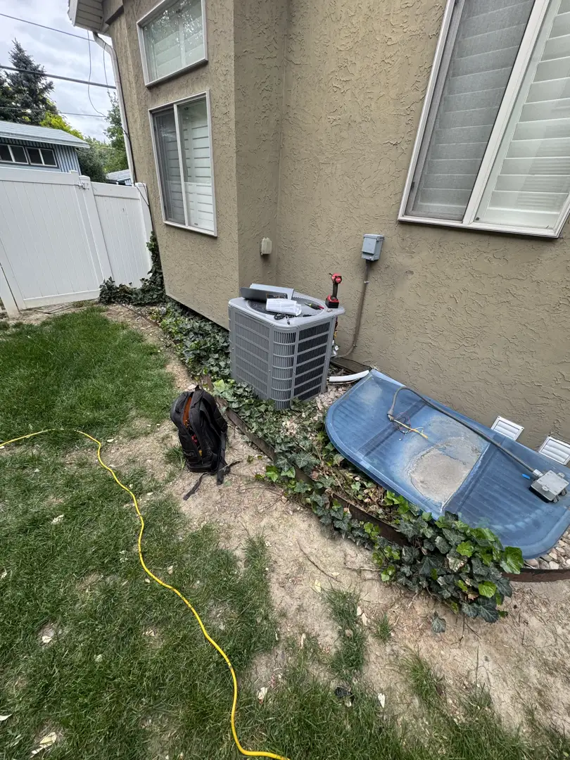 Technician inspecting an outdoor air conditioning condenser unit in a Kaysville residential backyard - ac maintenance in Technician inspecting an outdoor air conditioning condenser unit in a Kaysville residential backyard - ac maintenance in