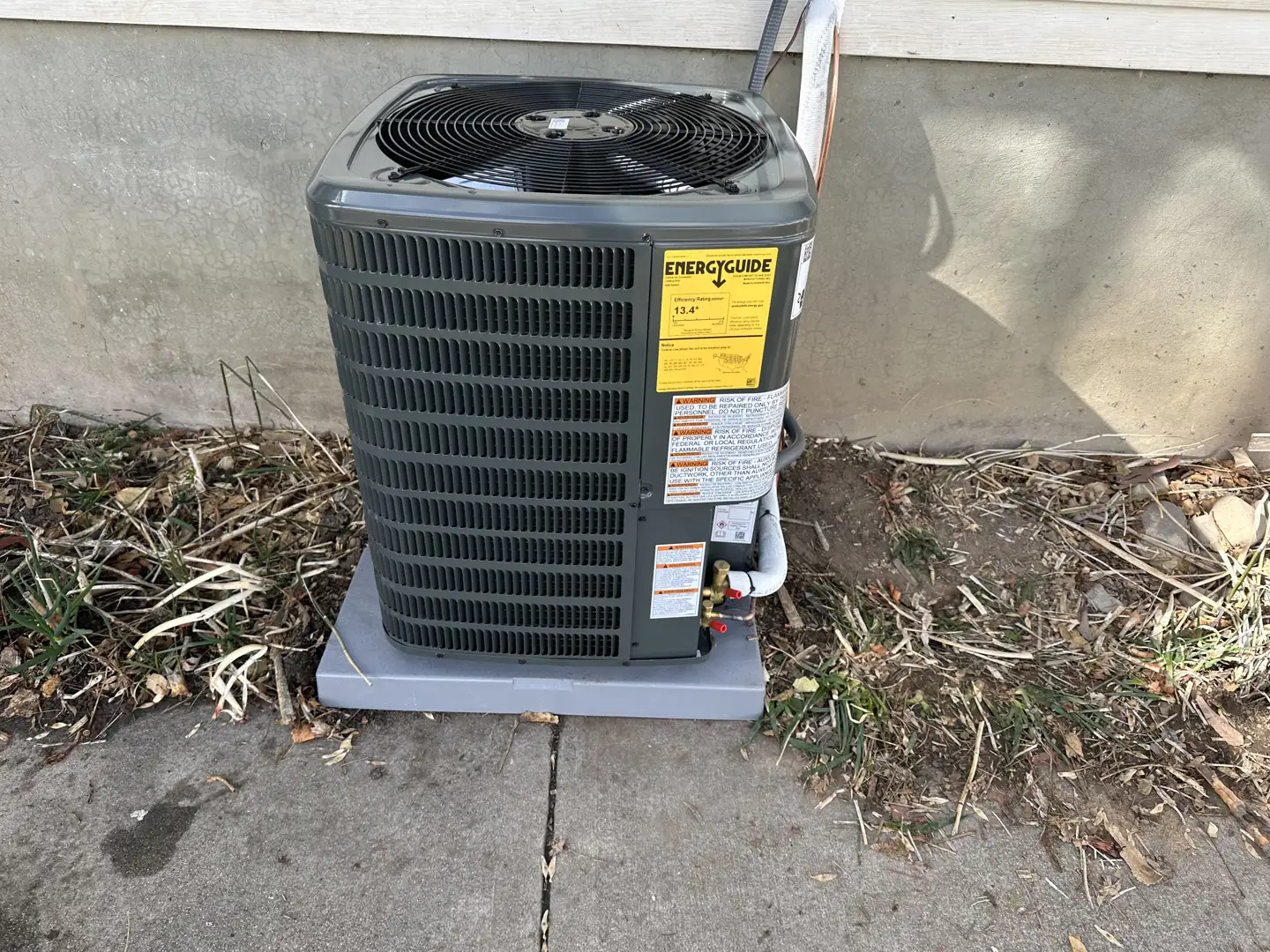 Outdoor central air conditioning unit on a clean concrete pad next to a residential home - affordable ac installation in