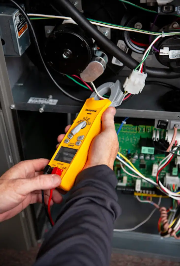 Technician testing electrical voltage on an AC contactor - ac tune up checklist what your technician should check Technician testing electrical voltage on an AC contactor - ac tune up checklist what your technician should check