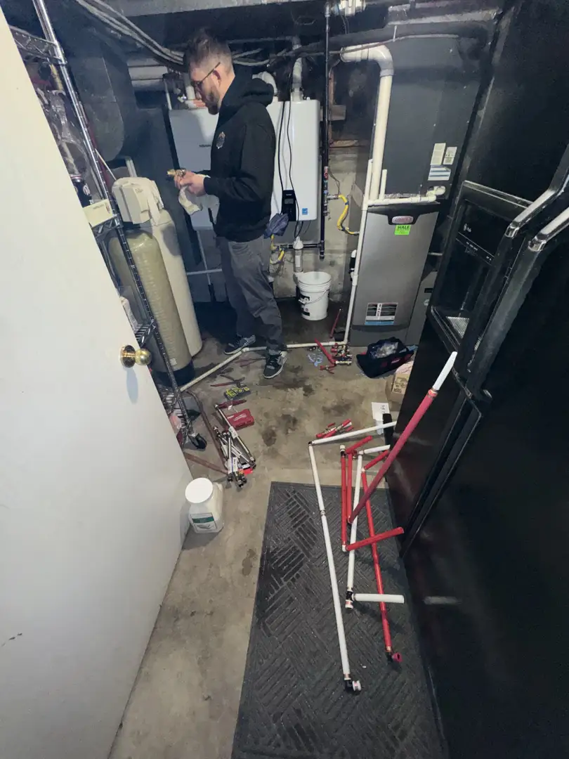 professional plumber installing new PEX pipes behind a drywall cutout professional plumber installing new PEX pipes behind a drywall cutout