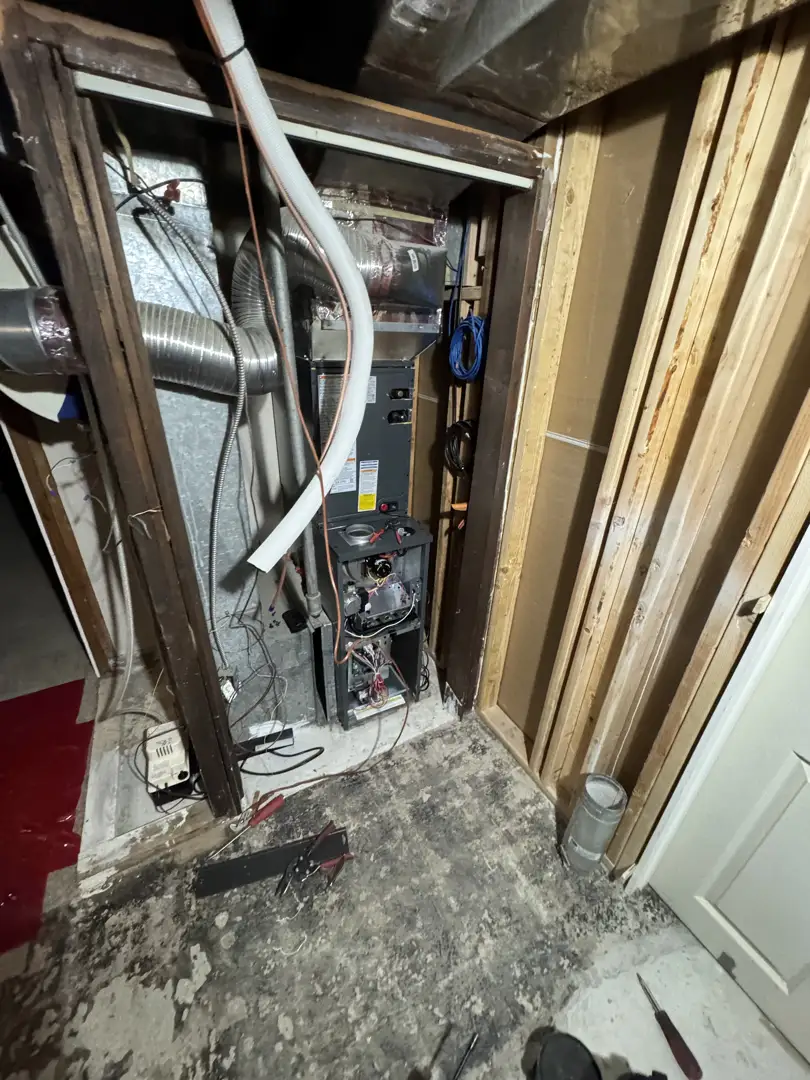 HVAC technician performing a professional pre-season inspection on a furnace system in a Utah basement HVAC technician performing a professional pre-season inspection on a furnace system in a Utah basement