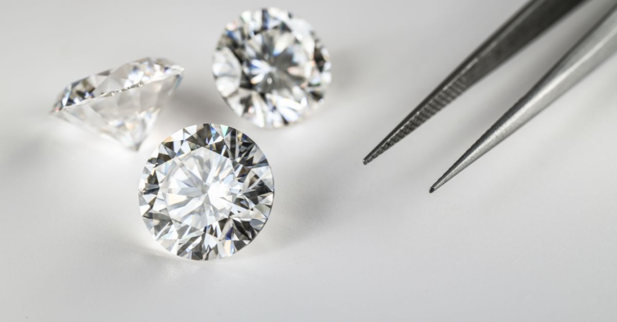Loose diamonds displayed beside tweezers during a professional jewelry evaluation