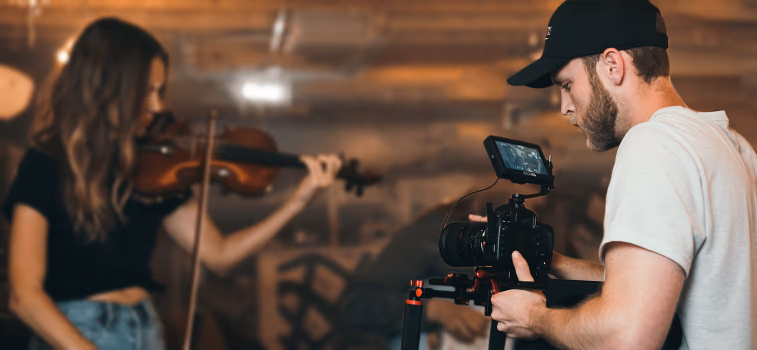A videographer filming a woman playing a violin