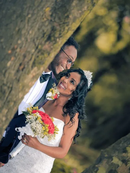 African bride and groom on their wedding day being filmed together by a tree